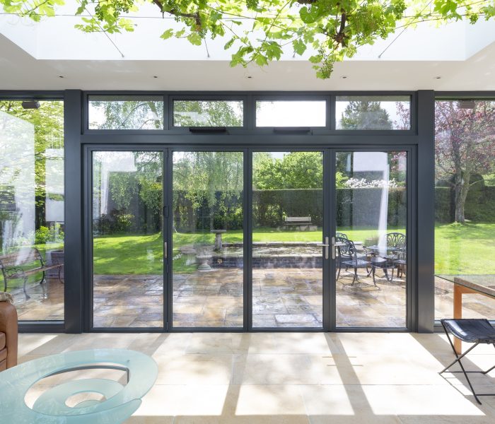 Visofold 6000 bifold door closed with glazed side and top panels overlooking a garden
